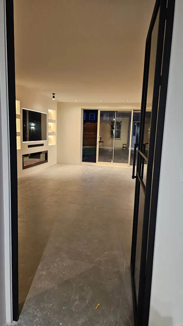 Verbouwde woning met zwarte stalen deur en open woonkamer