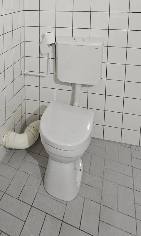 Staand toilet met het reservoir zichtbaar aan de muur