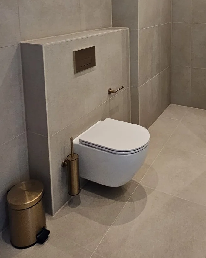 Zwevend toilet aan een betegelde voorzetwand, met vrije vloer eronder